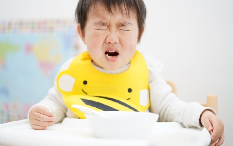 男の子が離乳食を前に食べすに大泣きしている様子。