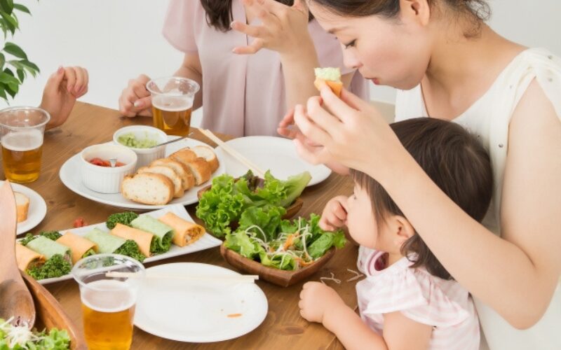 赤ちゃんが母親の膝の上に座り、ホームパーティーに参加している様子。