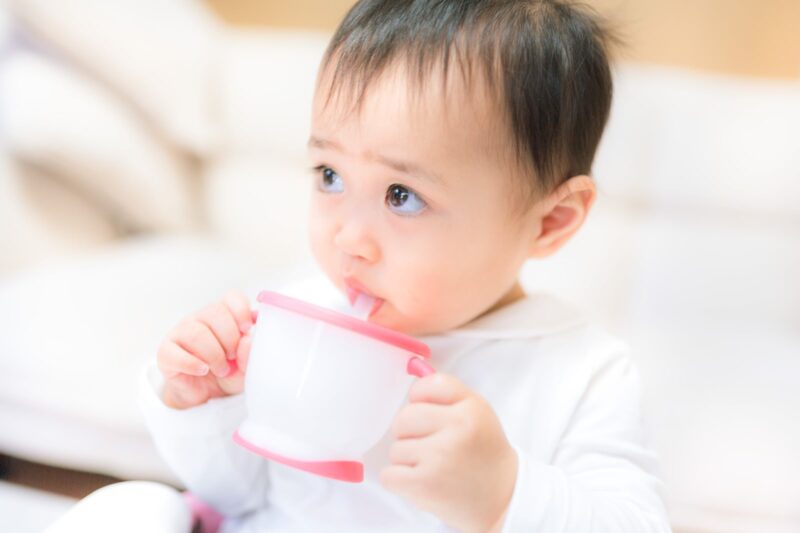 赤ちゃんがマグで飲み物を飲んでいる様子