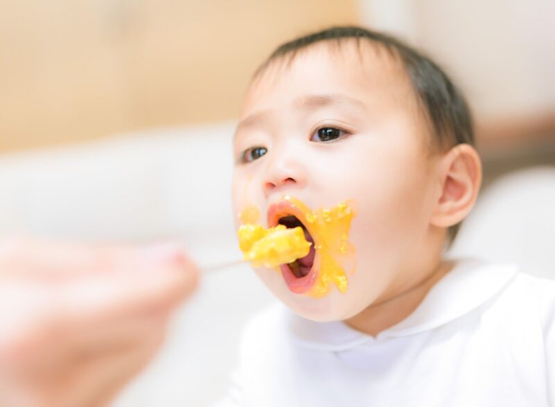 赤ちゃんスプーンで離乳食をたべている様子