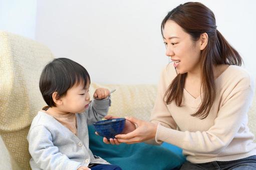 子どもが自分で食べるのをママがサポートしている様子