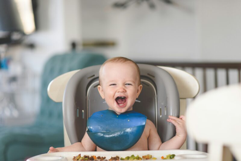 赤ちゃんが食事の前で笑っている