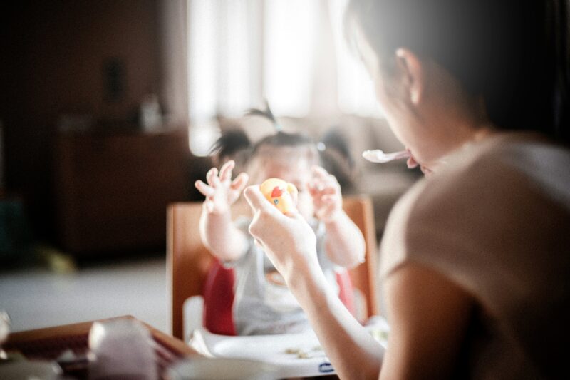 母親が赤ちゃんに離乳食を食べさせている様子